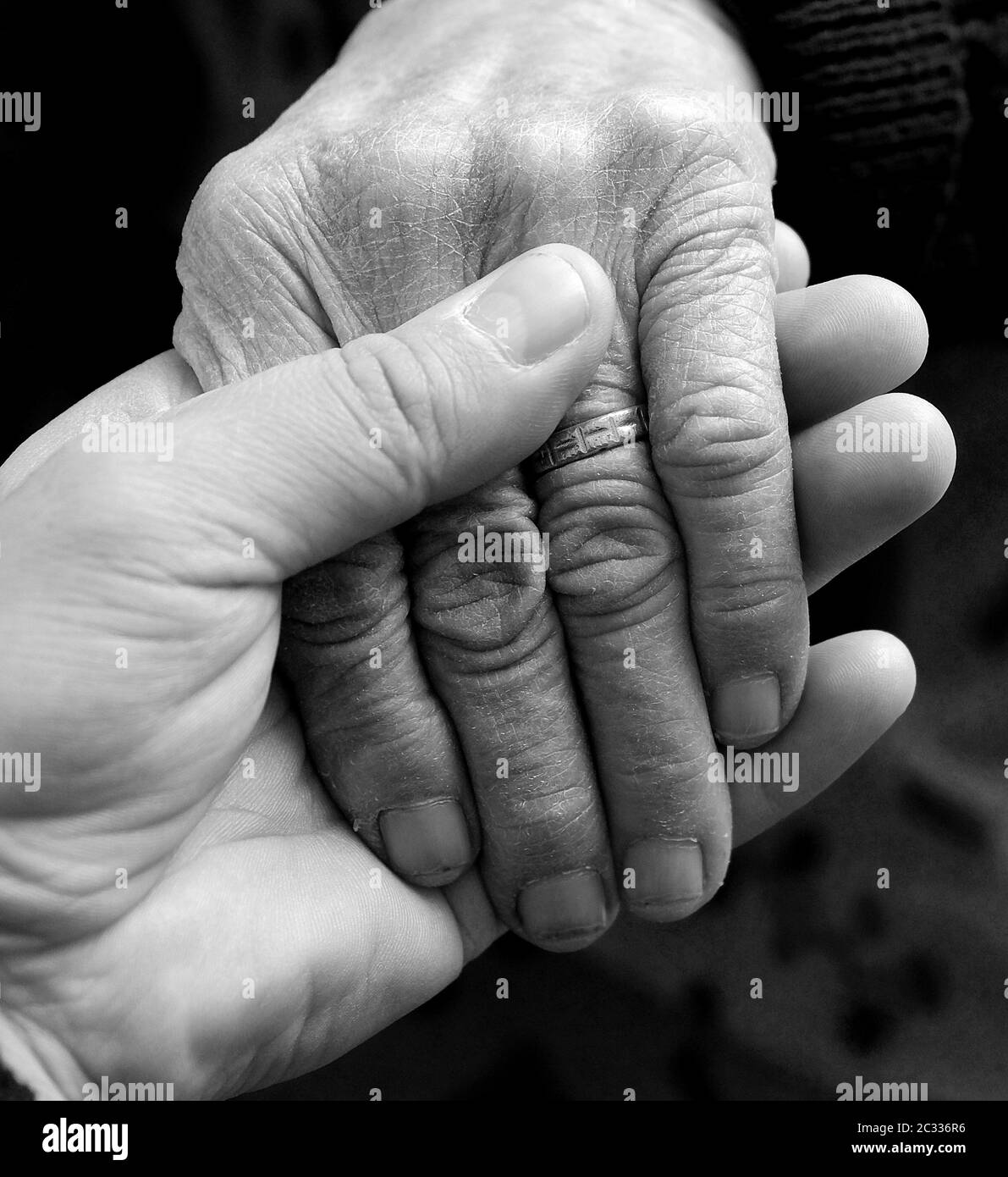 Ein junger Mensch hält zärtlich die Hand der Alten, Stockfoto