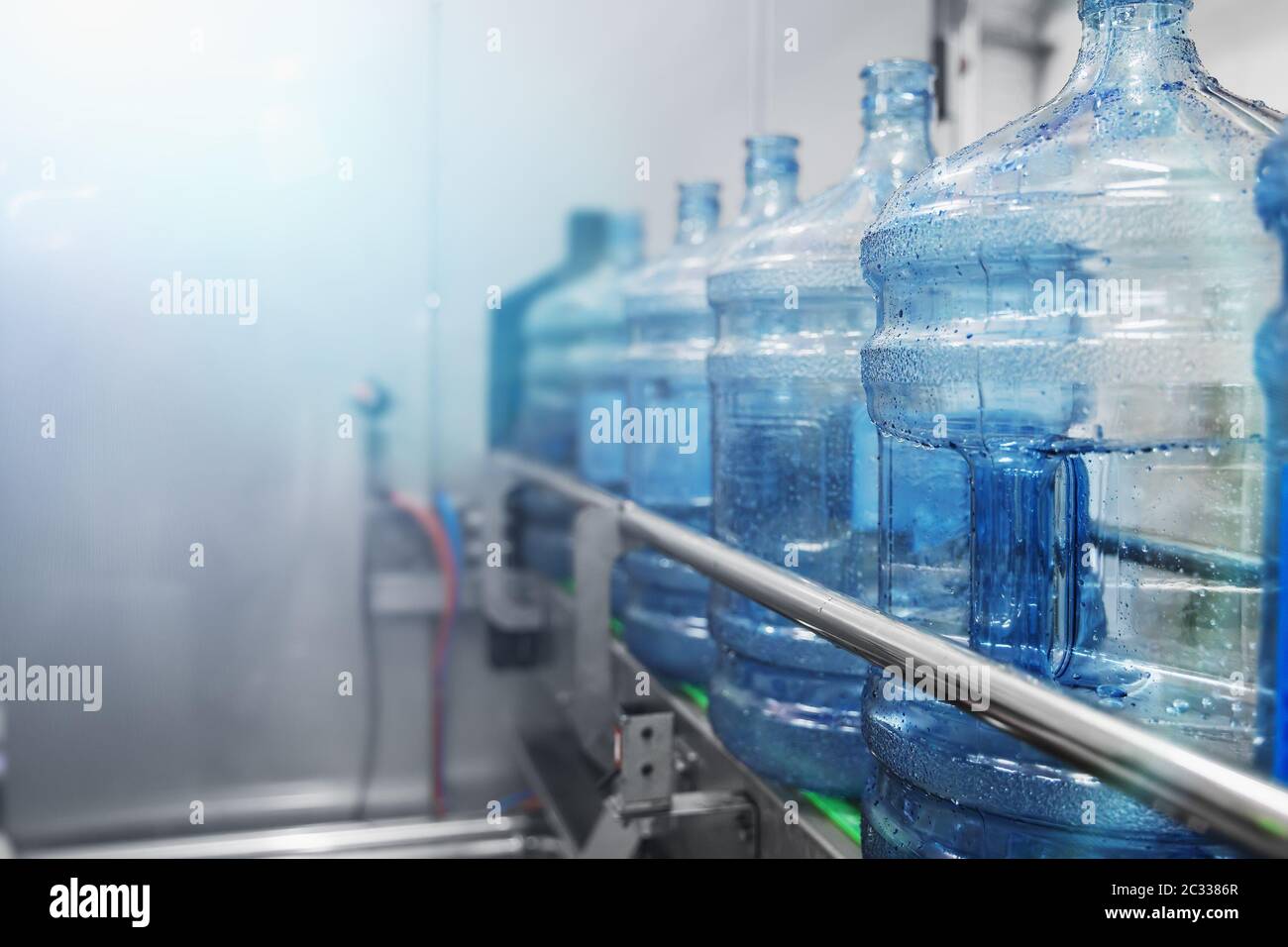 Wasserabfüllung Förderlinie mit Kunststoffflaschen oder Gallonen auf Wasser Fabrik Produktion, selektive Fokus für Kopieplatz. Stockfoto