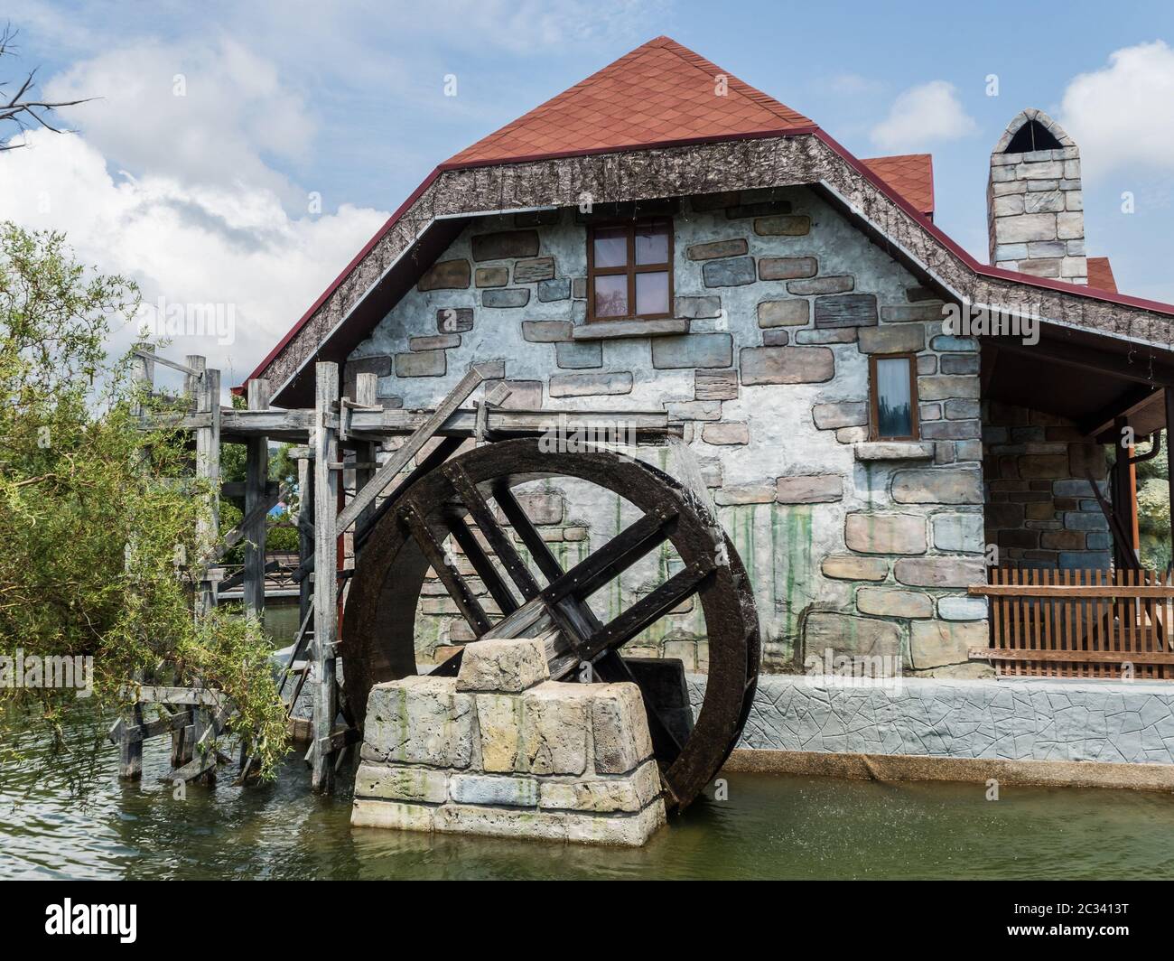 Hölzerne Wasserrad auf dem Hintergrund eines Steinhauses im Park Russland Sotschi 22 06 2019 Stockfoto