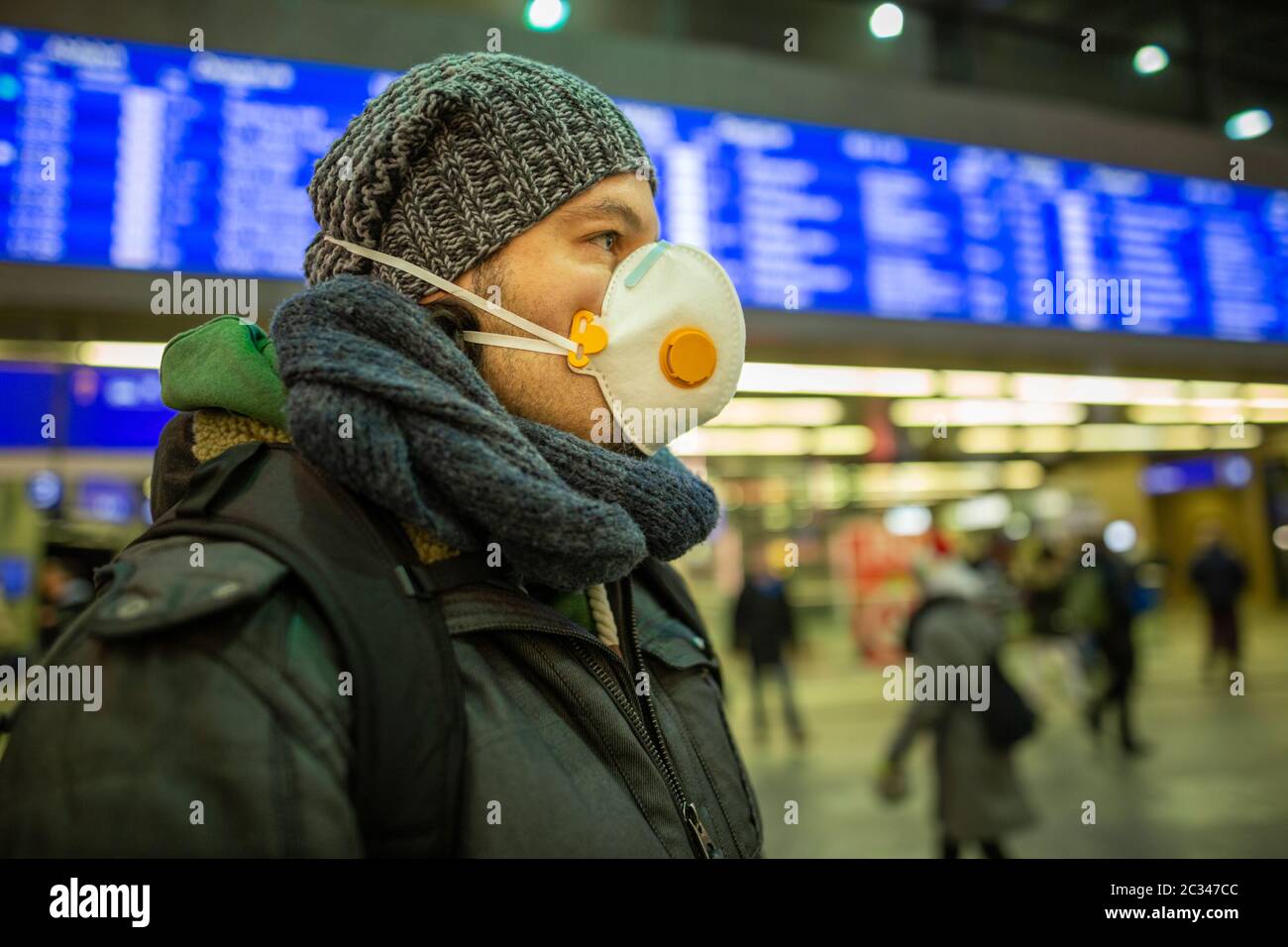 Mann mit Atemschutzmaske zum Schutz der Gesundheit auf einem Flughafen oder Bahnhof in Stockfoto