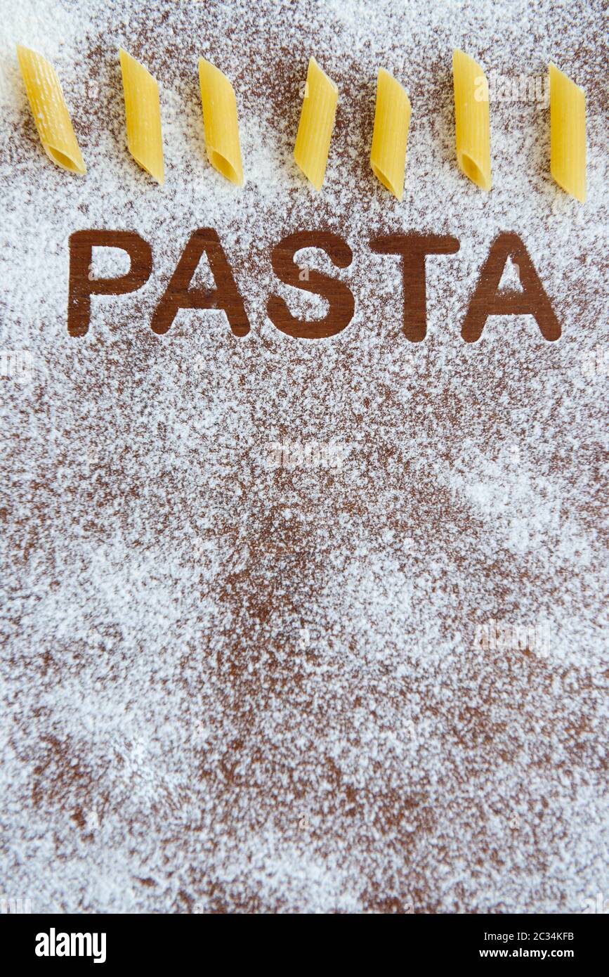 Holzhintergrund mit bestreut Mehl und das Wort Pasta geschrieben. Stockfoto