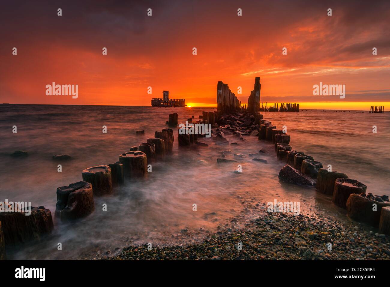 Dramatischer Sonnenaufgang über dem Meer. Berühmter Ort an der Ostseeküste, Strand in der Nähe der alten Torpedos aus dem 2. Weltkrieg Stockfoto