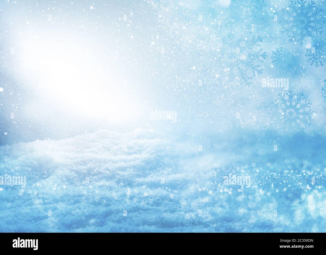 Verwischtes blaues Schneelandgebiet mit hellem magischen Lichtstrahl und Eiskristallen. Hintergrund für ein winterliches weihnachtskonzept. Platz für Text. Stockfoto