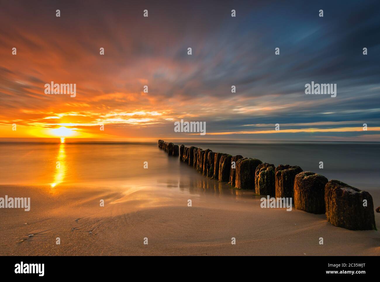 Schöner Sonnenuntergang an der Ostsee, Wellen waschen die alten hölzernen Wellenbrecher Stockfoto