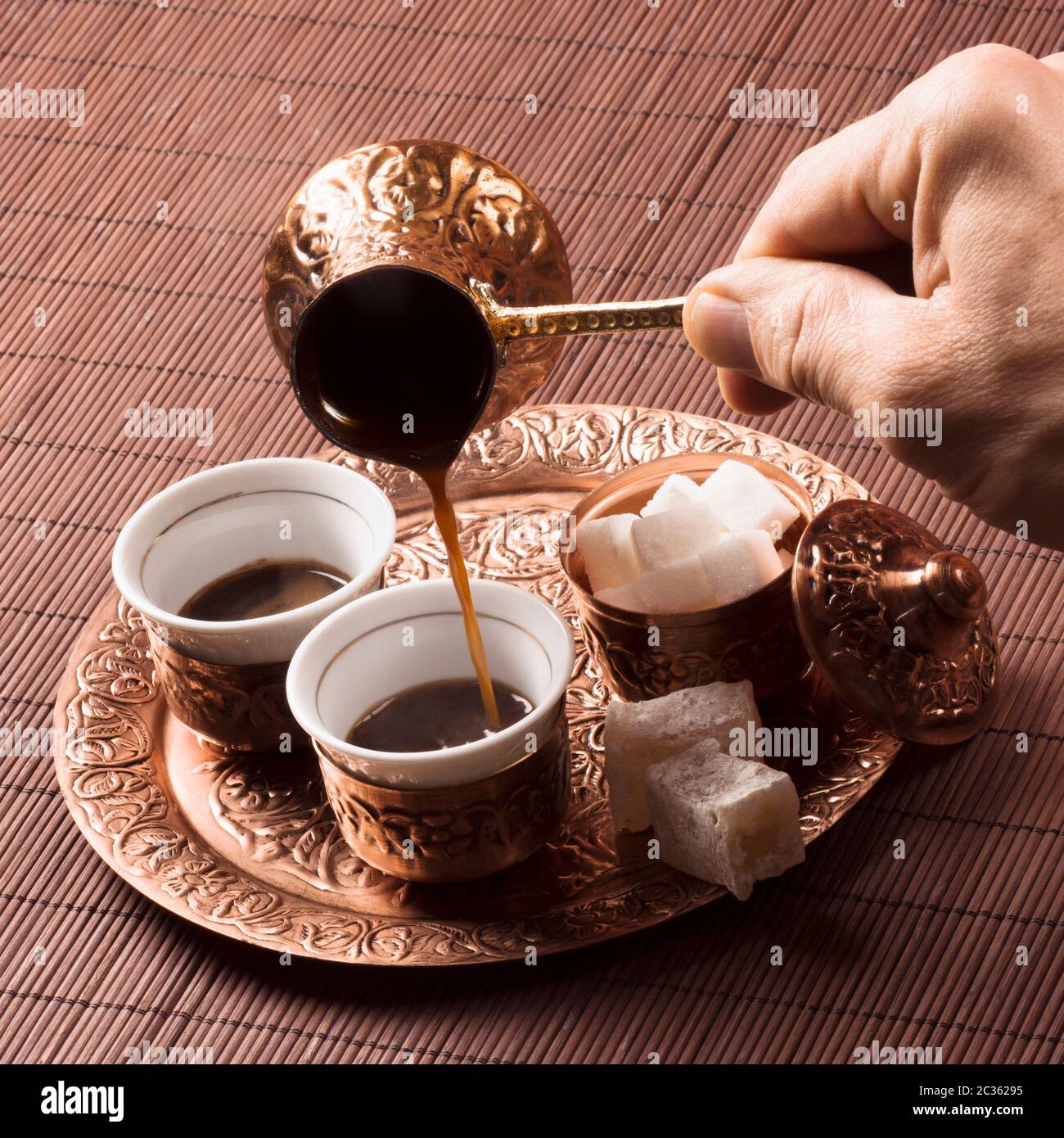 Die männliche Hand gießt Kaffee in Tasse Kaffee, Kupfer türkischen Kaffee-Set. Stockfoto