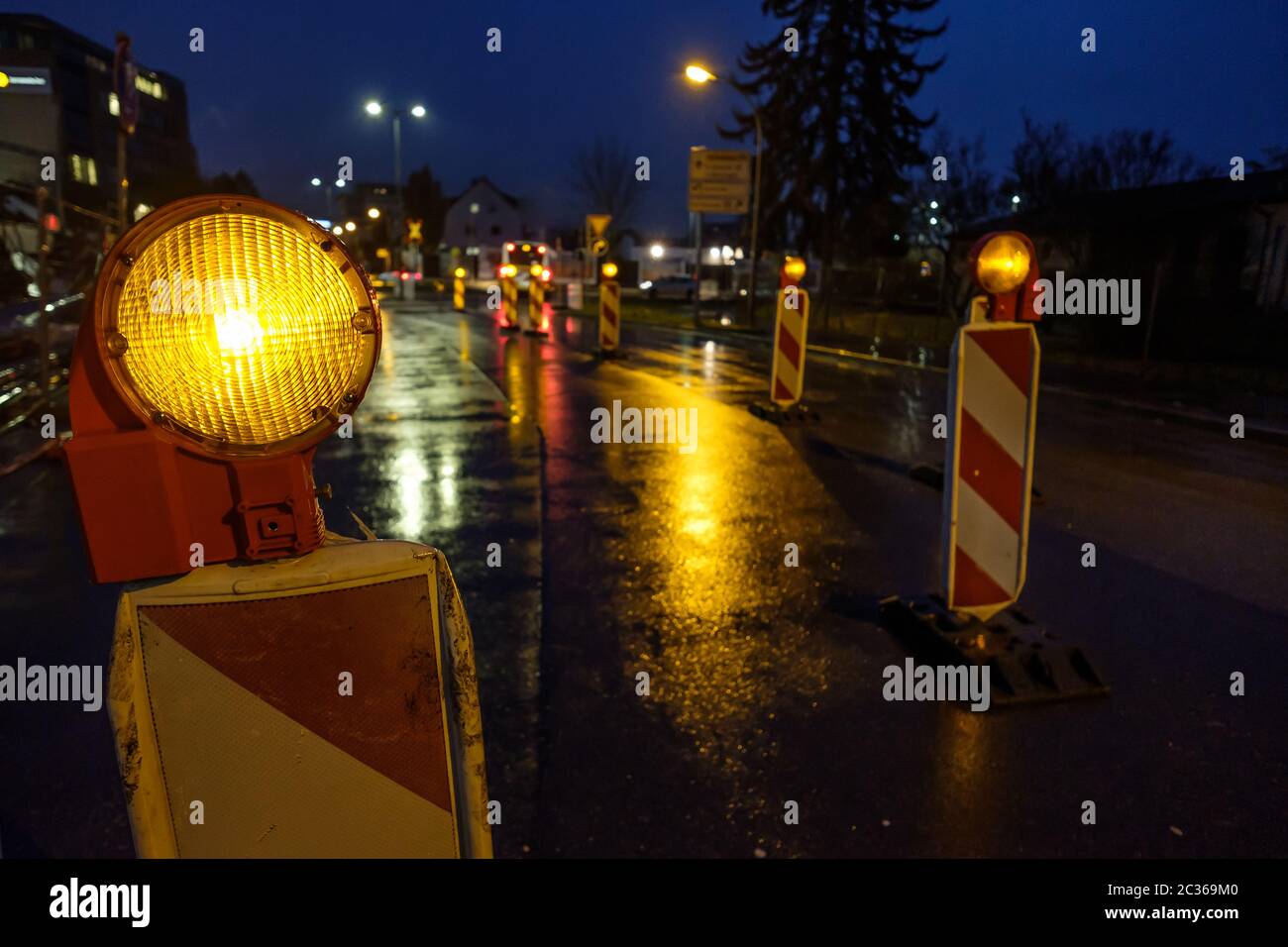 Warnleuchte an einer Baustelle mit nassen Straße Stockfoto