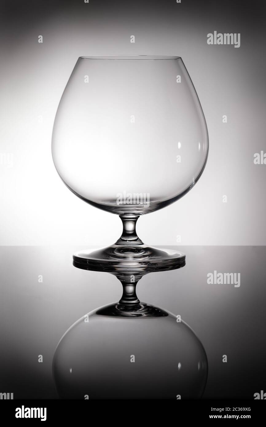 Brandy und Cognac Glas in der Hintergrundbeleuchtung mit Reflektion Stockfoto