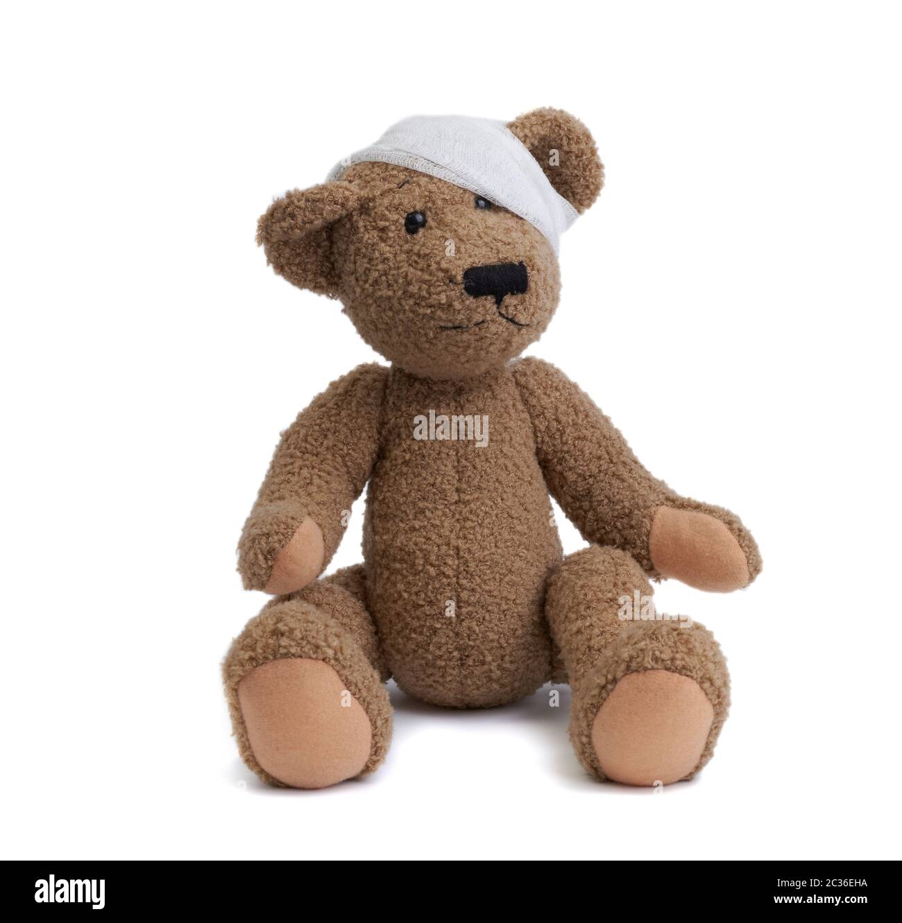 Brauner Teddybär mit einem Bandenkopf in einem weißen medizinischen Verband auf weißem Hintergrund, Konzept des Kindertraumas, Kopfschmerzen Stockfoto