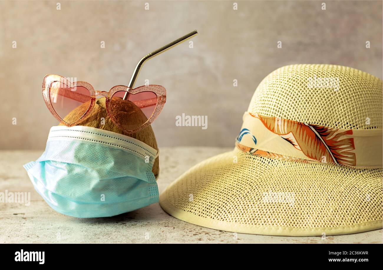 Kokosnuss in Sonnenbrillen und medizinische Masken und Stroh Strandhut. Stockfoto
