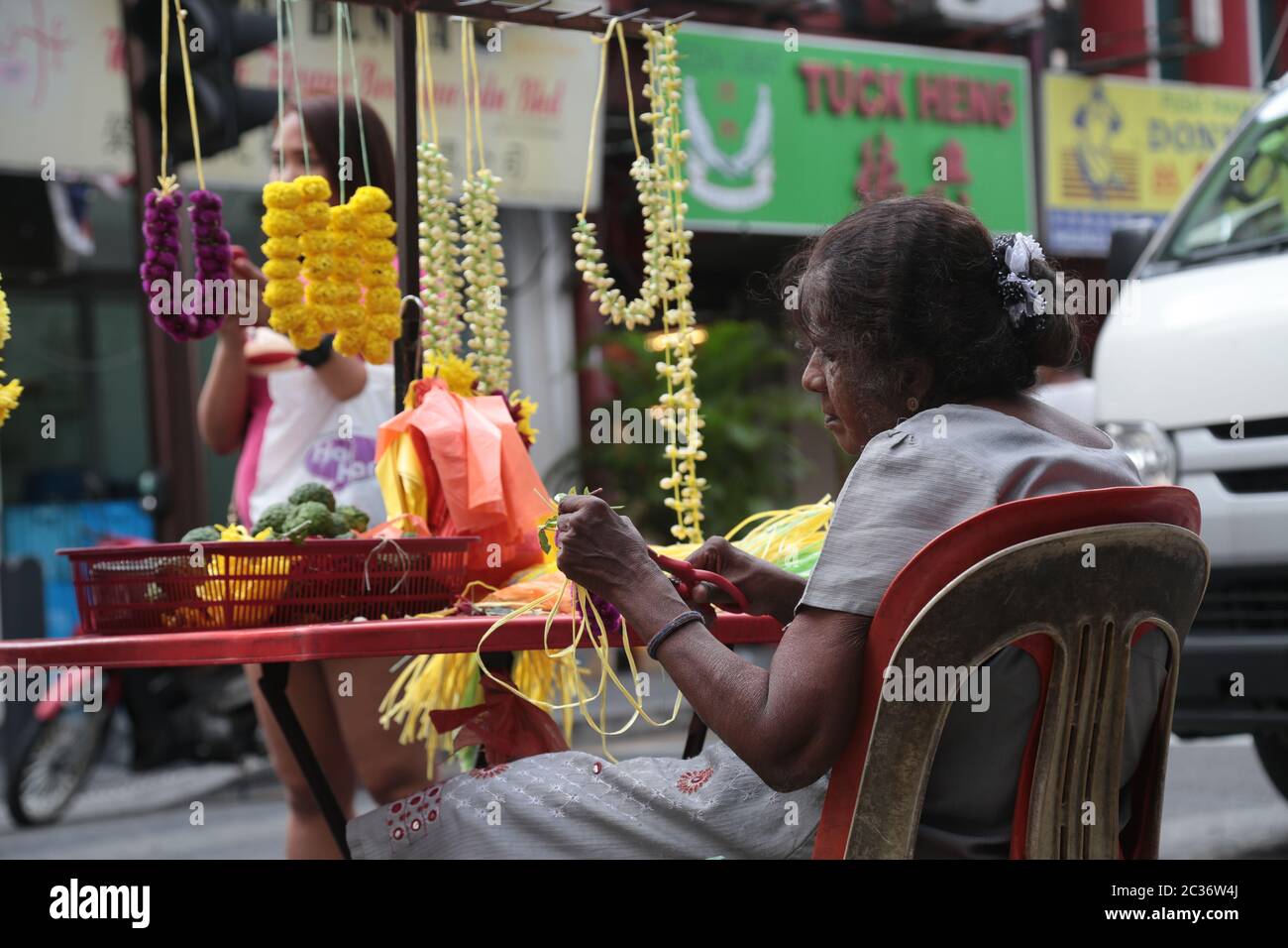 Alte indische Dame verkauft handgemachte Blumengirlande entlang einer Stadtstraße in Kuala Lumpur, Malaysia. Stockfoto