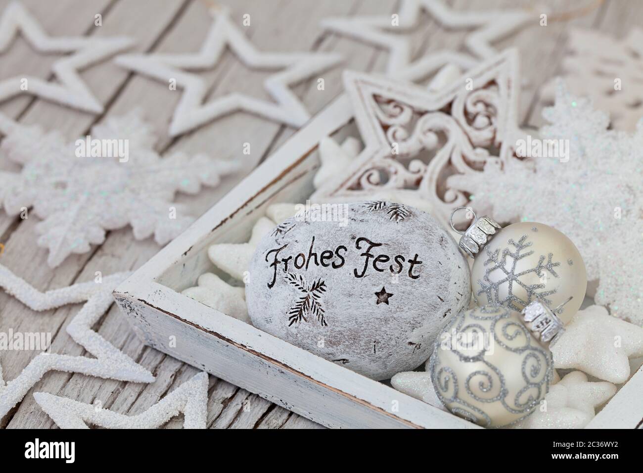 nordisches weihnachtsstillleben mit weißen und silbernen Ornamenten und Stein mit deutschem Text für Happy Holidays auf weiß gewaschenen Holz Stockfoto