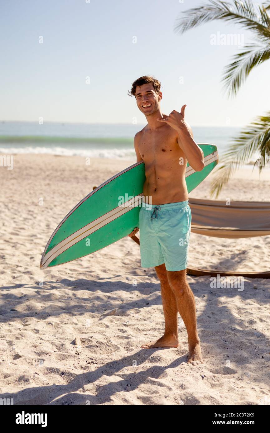 Kaukasischer Mann hält Surfbrett am Strand Stockfoto