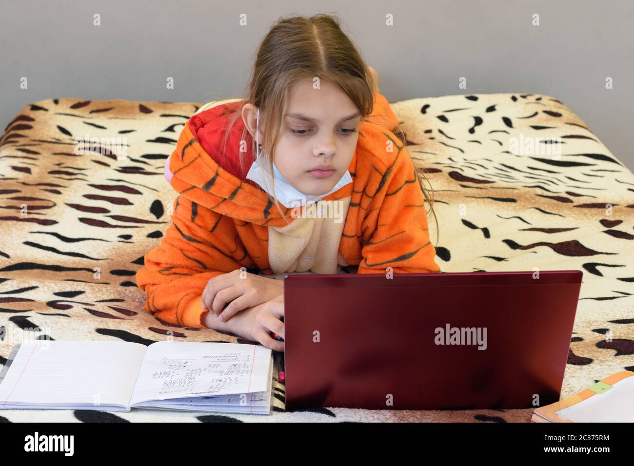 Ein krankes, unter Quarantäne geganges Mädchen lernt mit einem Laptop aus der Ferne Stockfoto