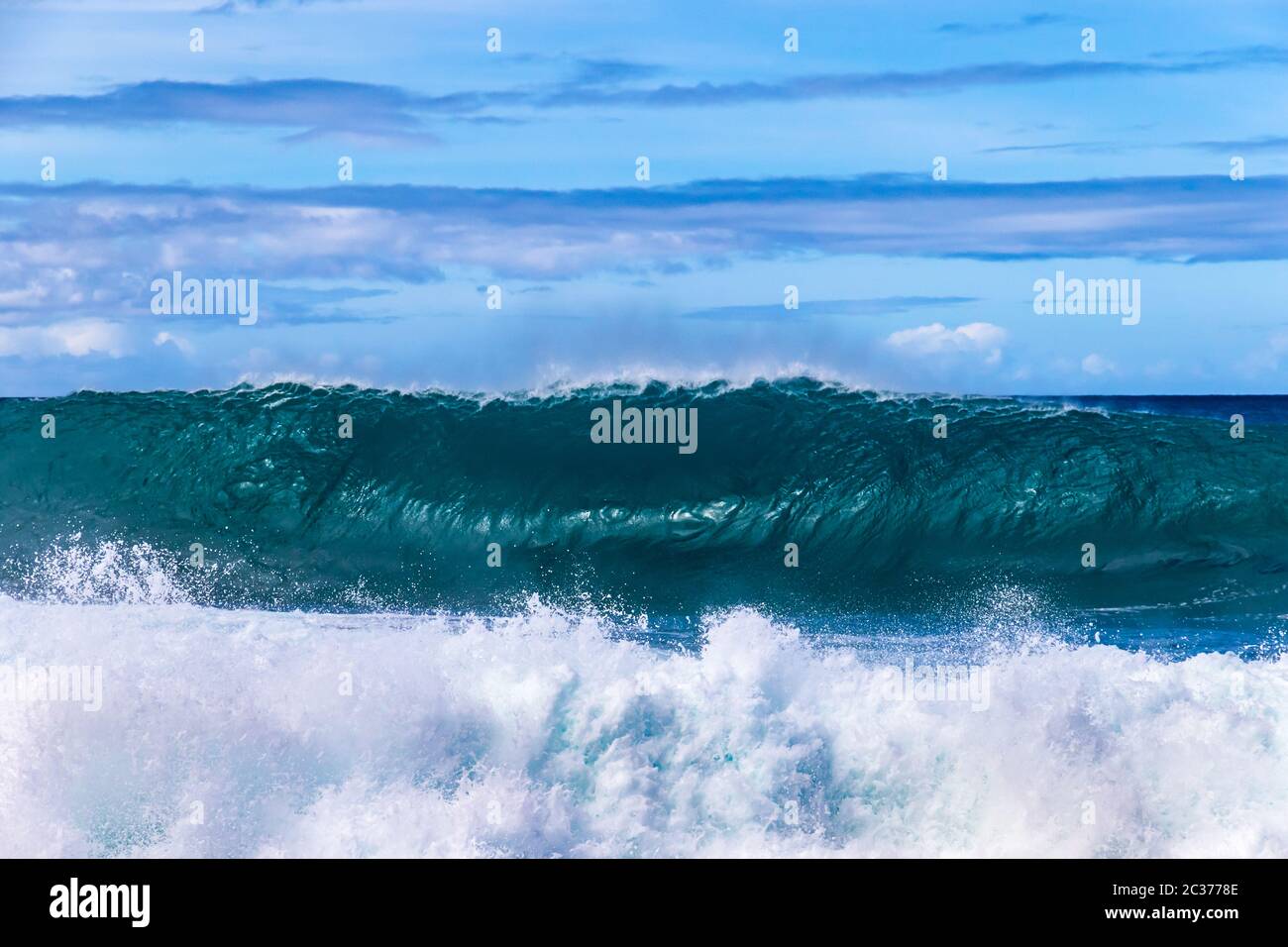 Wellenbrecher an der westlichen Kona Küste von Hawaiis Big Island. Spray und Schaum im Vordergrund. Pazifik, Himmel mit Wolken dahinter. Stockfoto