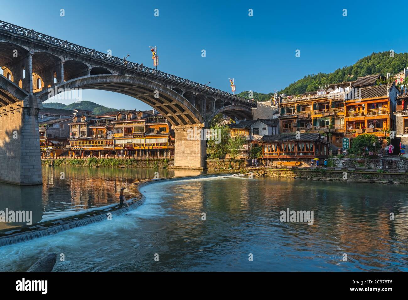 Feng Huang, China - August 2019: Lange Zeit ist die Verbindung der Straßenbrücke über den Fluss Tuo Jiang und Holzhäuser in der alten Altstadt von Fenghuang bekannt Stockfoto