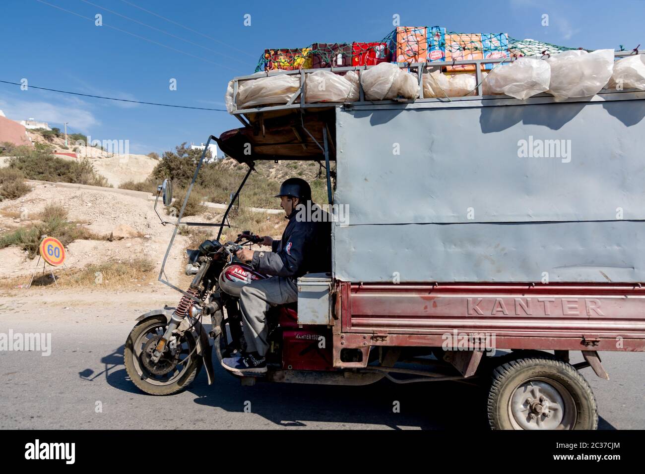 Marokko, Nordafrika, Feb 2019: Muslimischer Mann Fahrer in altem Fahrzeug Transport, Lieferung von Waren. Verkehr in Marokko auf schmutziger Straße in kleinem Dorf Stockfoto