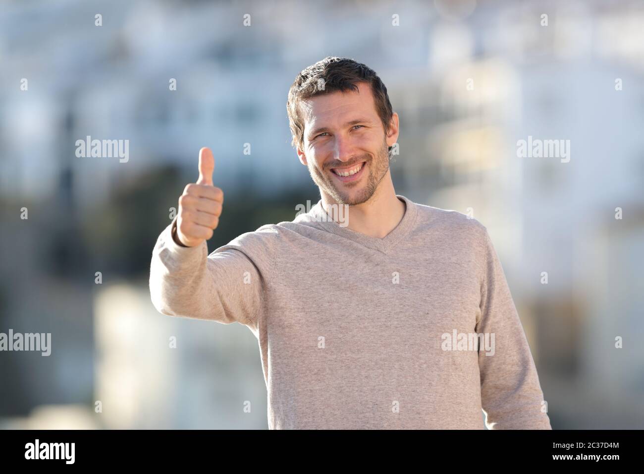 Vorderansicht Portrait eines glücklichen erwachsenen Mann deutete Daumen hoch stehend in einer ländlichen Stadt an einem sonnigen Tag Stockfoto