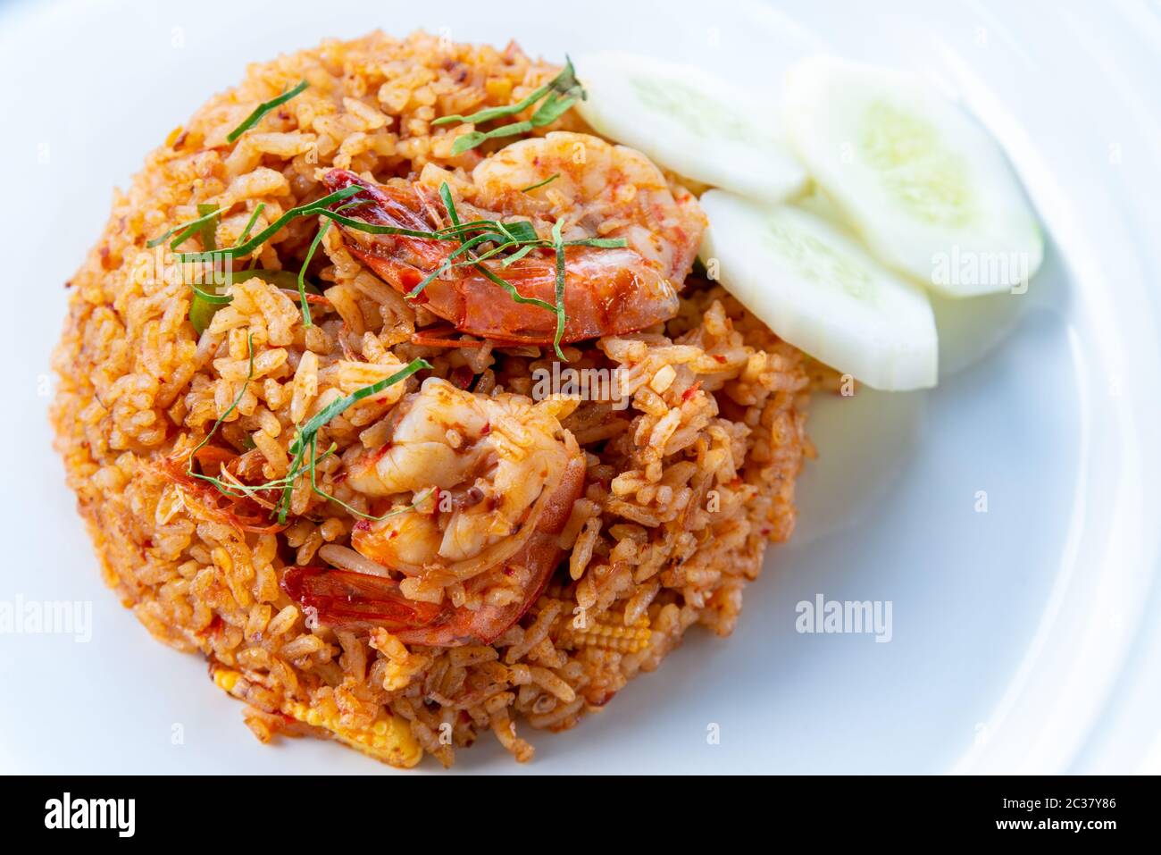Pikante thailändische Küche oder asiatische Küche Closeup Draufsicht Garnele Red Curry Fried Rice Meeresfrüchte, Garnierung mit zerfetzten Kaffir-Kalkblättern und geschnittene Gurken auf einem c Stockfoto