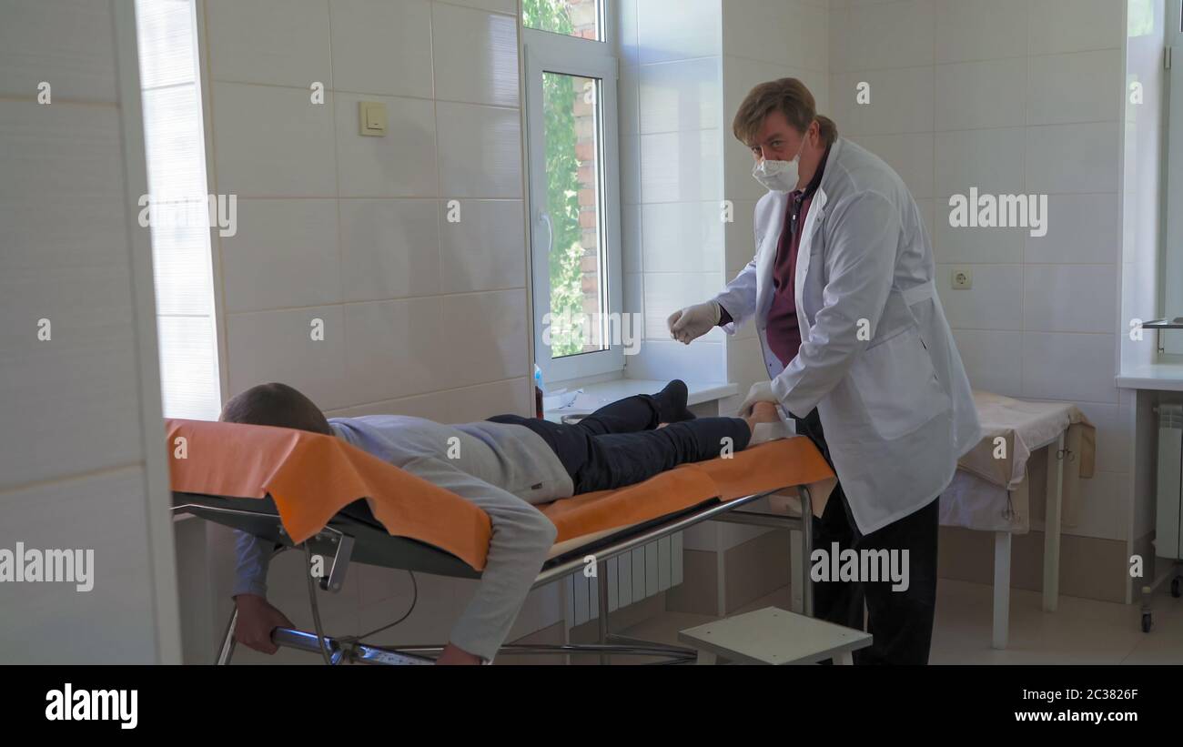 Der Arzt behandelt Patienten. Der Chirurg führt eine Operation durch, die die Schmerzen im Bein des Patienten beseitigt. Stadtkrankenhaus. Mai 2020, Brovary, Ukraine Stockfoto