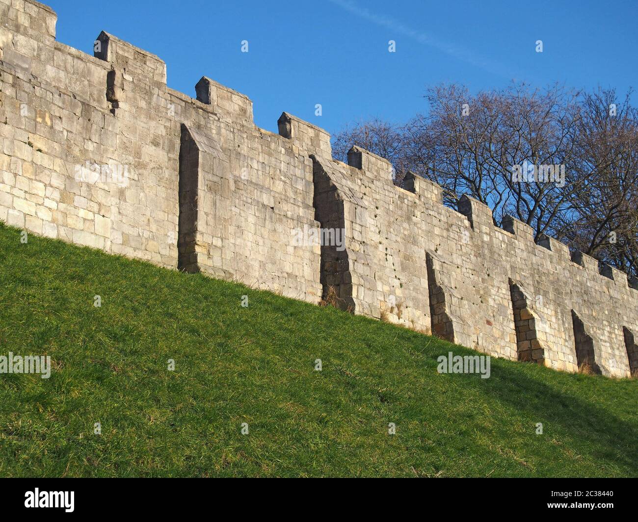 Ein Blick auf die alten mittelalterlichen Stadtmauern von york mit Gras bedeckt Böschung und blauen Himmel Stockfoto