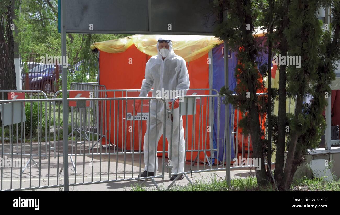 Der Arzt im Anzug des epidemiologischen Schutzes geht entlang des roten Korridors des höchsten Grades der Gefahr beim Eingang zum Krankenhaus. Gegenwirkung im Mittelpunkt Stockfoto
