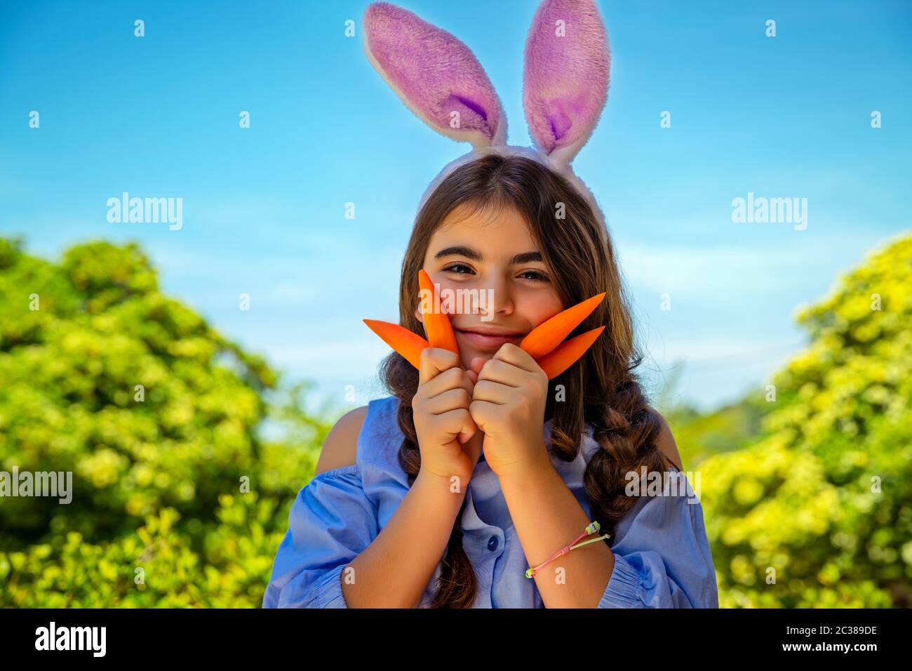 Portrait eines niedlichen kleinen Mädchens, gekleidet als Hünenspiel mit Karotten, Gartenarbeit und Spaß im Freien am sonnigen Frühlingstag, Osterfeier Outdoo Stockfoto