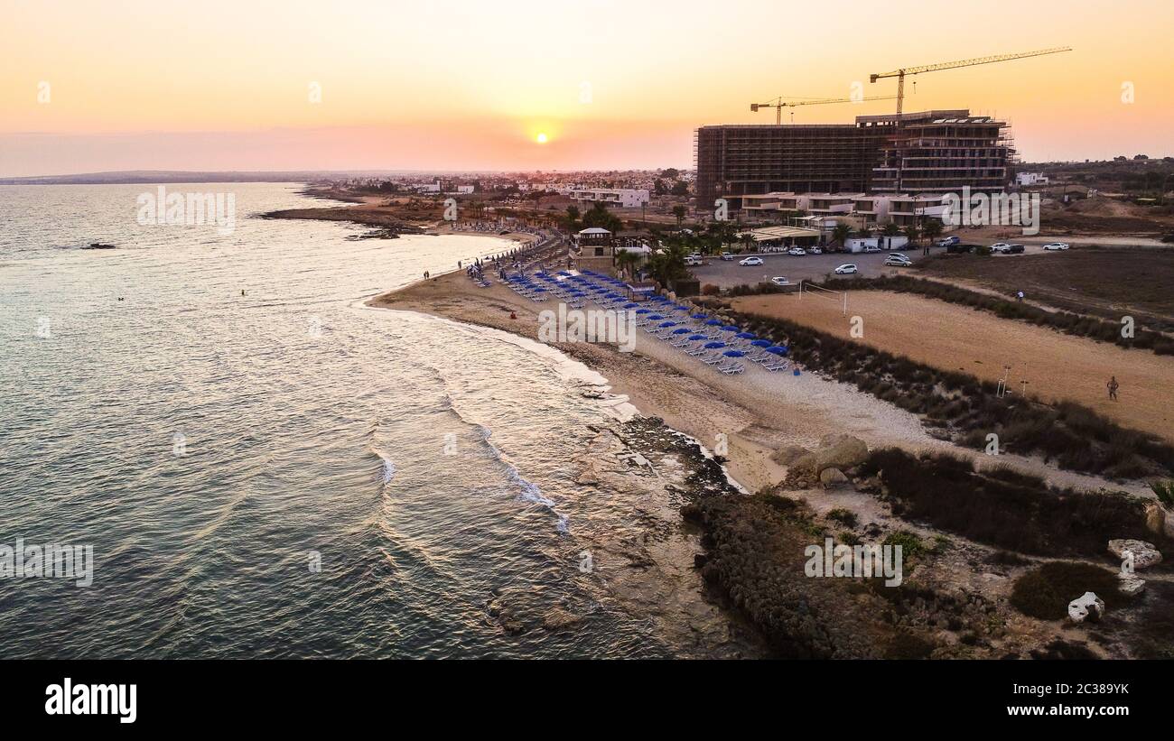 Blick auf den Sonnenuntergang an der Küste und den markanten Strand von Agia Thekla, Ayia Napa, Famagusta, Zypern von oben. Blick auf die Skyline von Vögeln auf Touristen Stockfoto