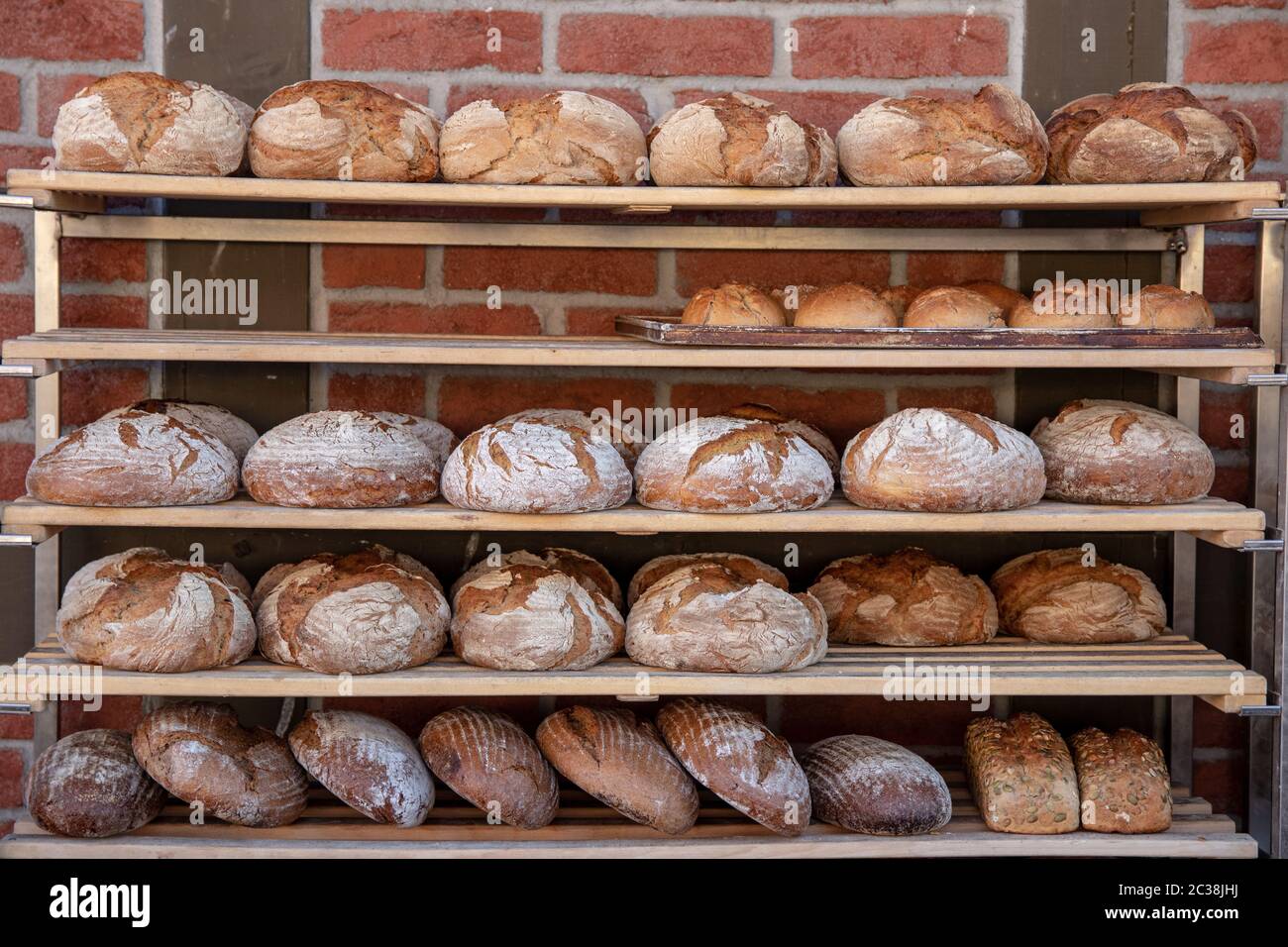 Backwaren. Eine Vielzahl von frisch gebackenem Brot in hölzernen Regalen eines Landes Bäckerei vor einer Mauer. Konzept gesunde Ernährung. Stockfoto