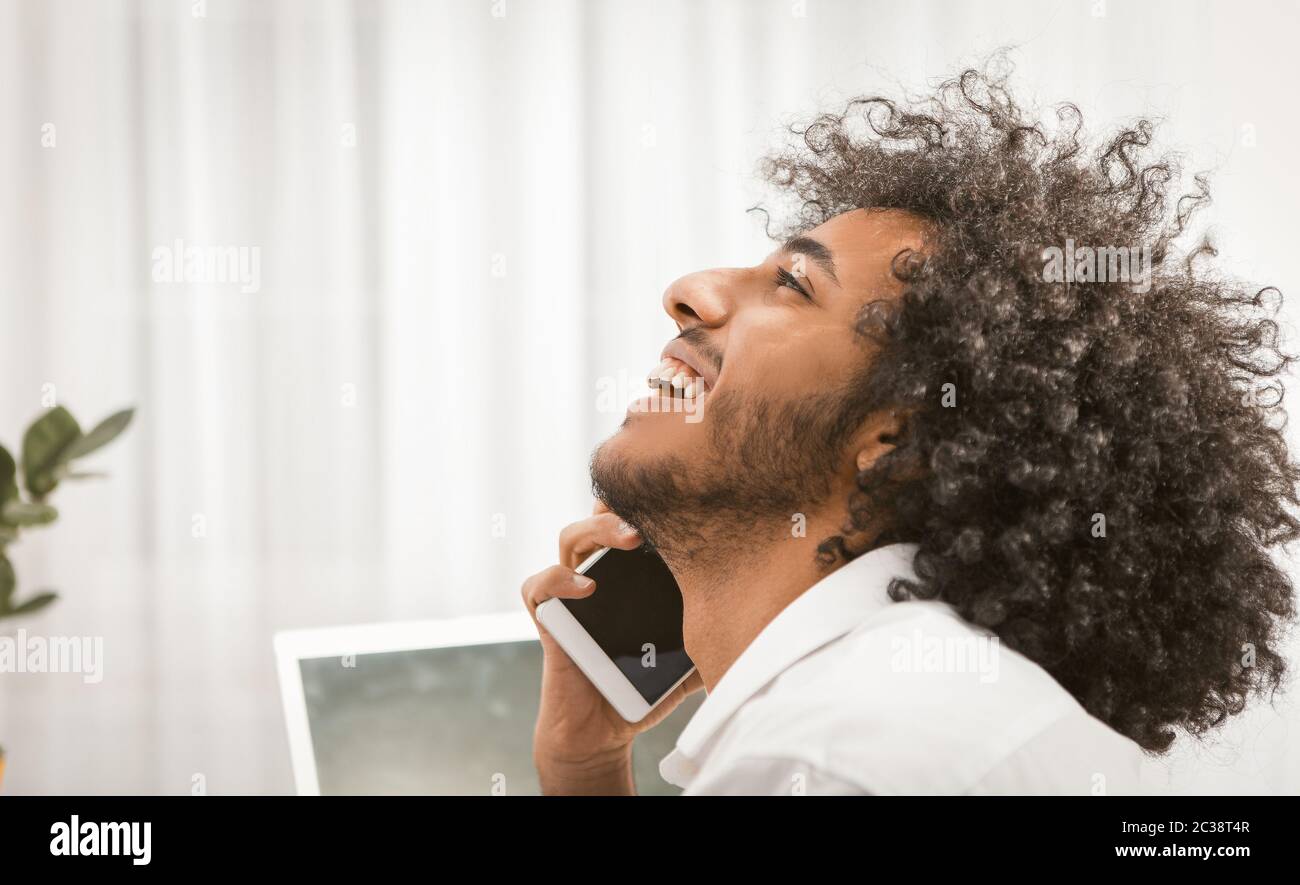Glücklicher Mann lächelt breit reden Handy auf weißem Hintergrund. Profilansicht des schönen arabischen Kerl reden am Telefon. Nahaufnahme im Hochformat. Getönt Stockfoto