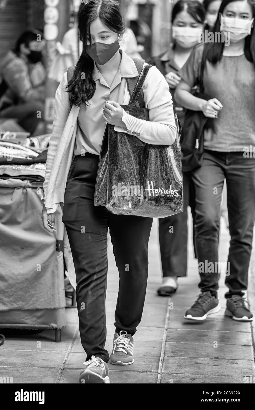 Mädchen trägt Gesichtsmaske zu Fuß mit Einkaufstasche während Covid 19 Pandemie, Bangkok, Thailand Stockfoto