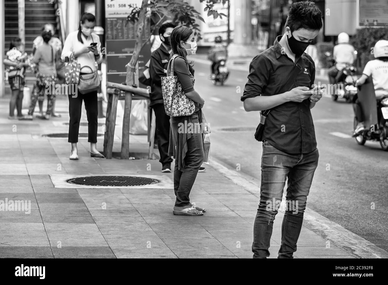 Passagiere mit Gesichtsmaske soziale Distanzierung an Bushaltestelle während Covid 19 Pandemie, Bangkok, Thailand Stockfoto