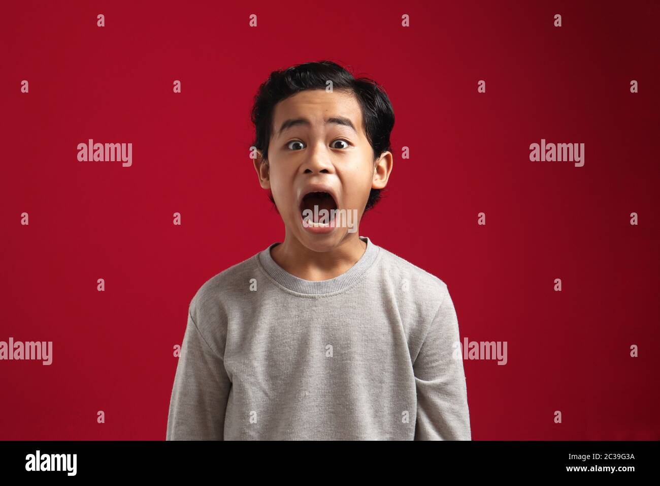 Junge asiatische junge Blick auf Kamera mit offenem Mund und großen Augen, schockiert überrascht wow verblüfft Ausdruck, um etwas erstaunlich zu sehen Stockfoto