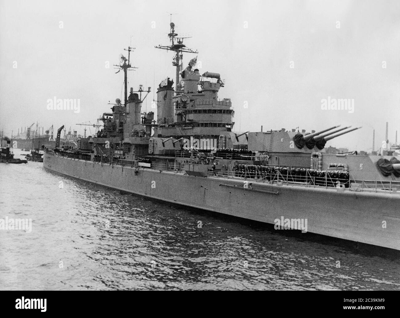 Die USS Macon (Baltimore-Klasse schwerer Kreuzer) der US Navy mit der Besatzung an Deck während eines Flottenbesuches in Hamburg in den 1950er Jahren. Stockfoto