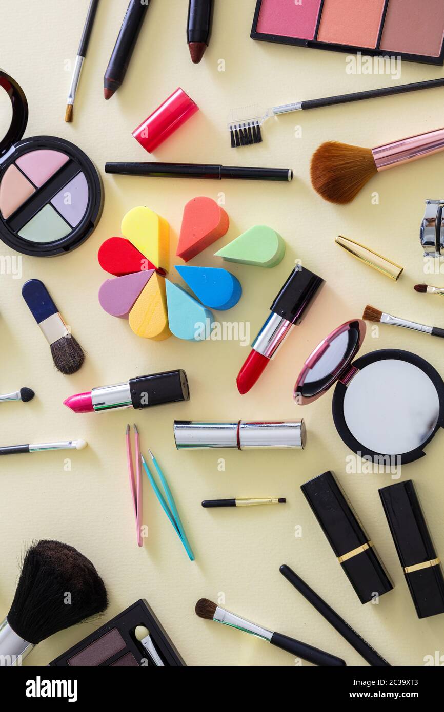 Make-up Kosmetik flach legen. Lippenstift und Nagellack, Lidschatten und Rouge, Pinsel und Bleistifte vor gelbem Hintergrund, Draufsicht Stockfoto