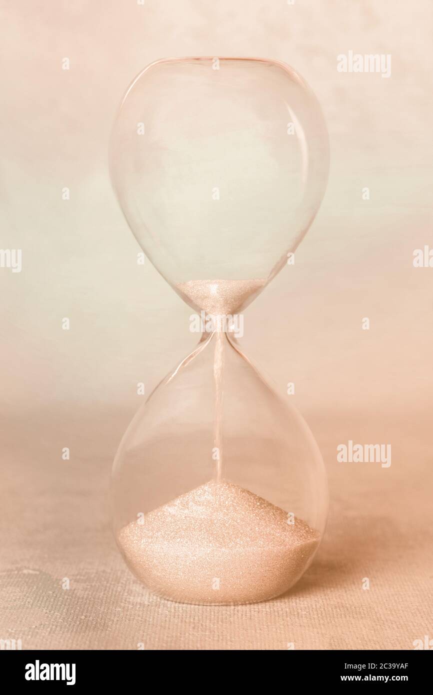 Zeitkonzept. Eine Sanduhr auf abstraktem Hintergrund. Sepia-getontes Bild Stockfoto