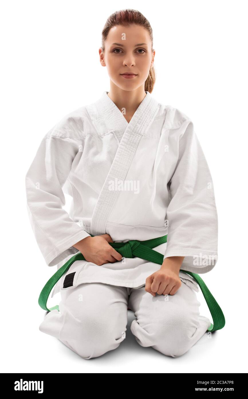 Porträt einer schönen Kampfkunstkämpferin in einem weißen Kimono mit grünem Gürtel in Seiza-Position, isoliert auf weißem Hintergrund. Ruhig, jung Stockfoto