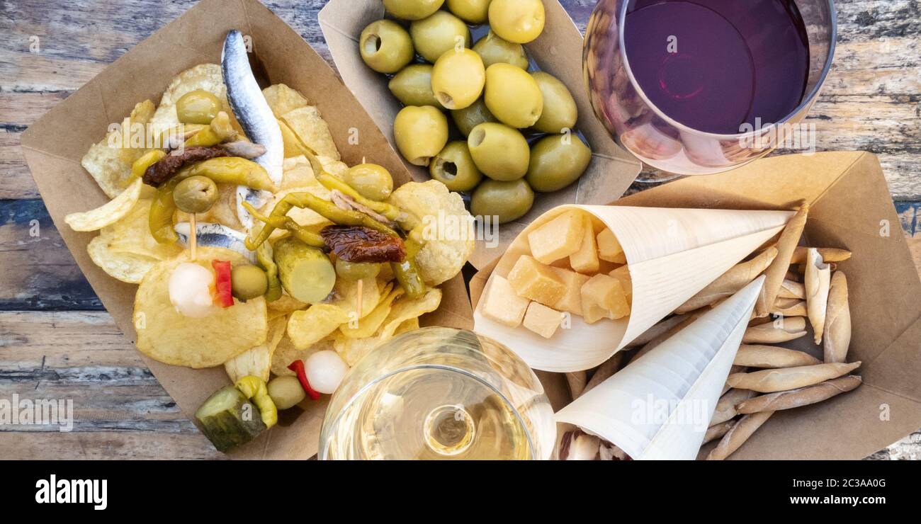 Tapas und Pinchos, Panorama. Käse, Jamon und Oliven, gildas und Kartoffelchips, mit Gläsern Rot- und Weißwein, On Stockfoto