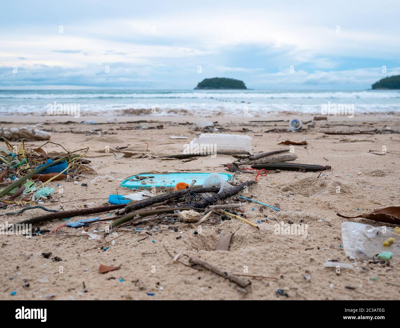 Umweltverschmutzung. Ökologisches Problem. Garbages, Plastik und Abfälle auf dem Sandstrand des tropischen Meeres. Insel und Berg Hintergrund. Stockfoto
