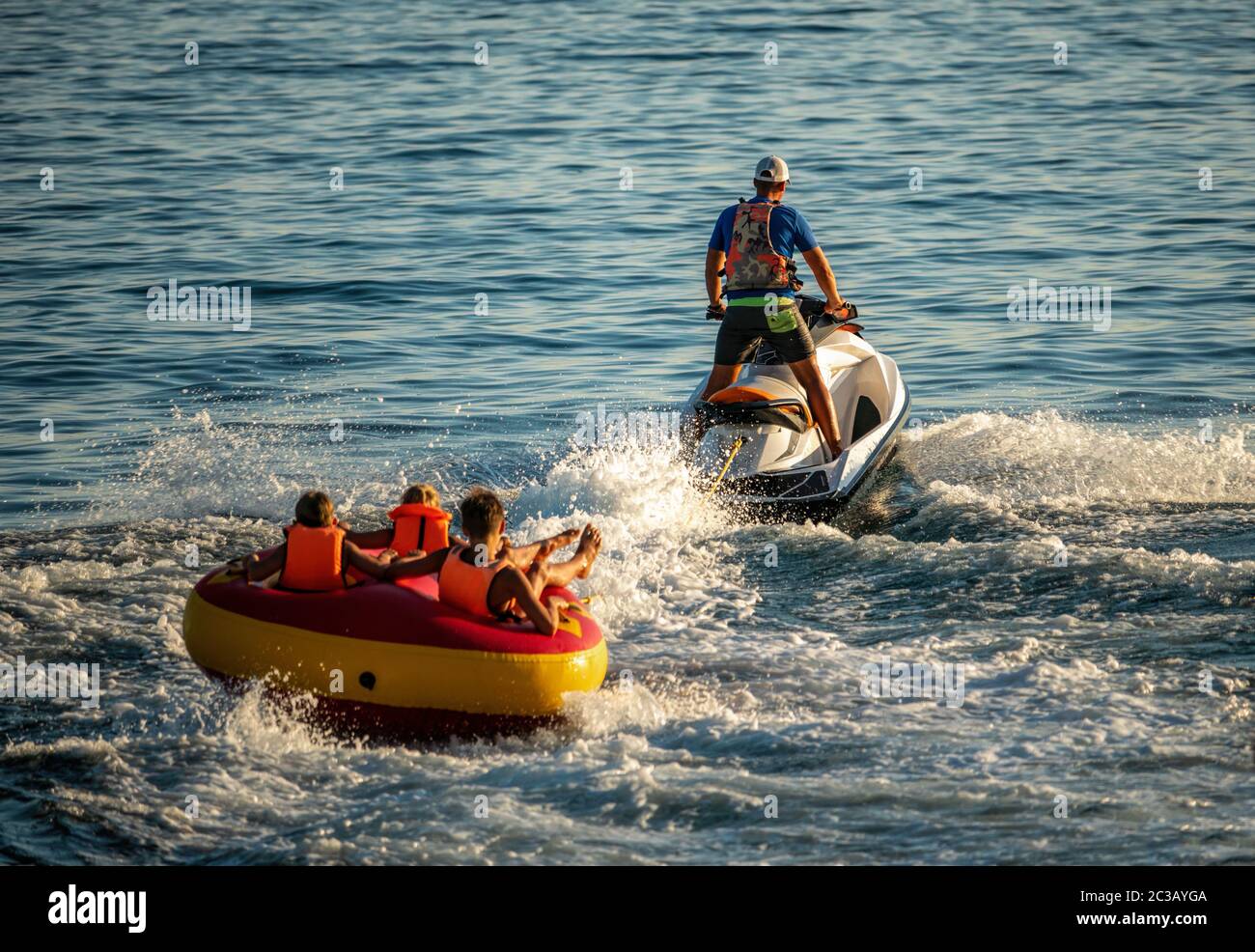 Aufblasbare Attraktion. Glückliche Leute schwimmen auf einer Luftmatratze  hinter einem Jet Ski. Touristen fahren das Schlauchboot. Jet-Ski-Skati  Stockfotografie - Alamy