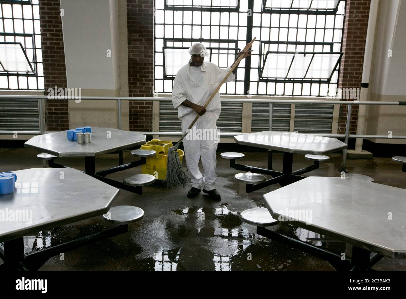 Rosharon Texas, USA, August 25 2014: Uniformierter männlicher Insasse im Hochsicherheitsgefängnis Darrington wischte den Boden in der Cafeteria des Gefängnisses. ©Marjorie Kamys Cotera/Daemmrich Photography Stockfoto