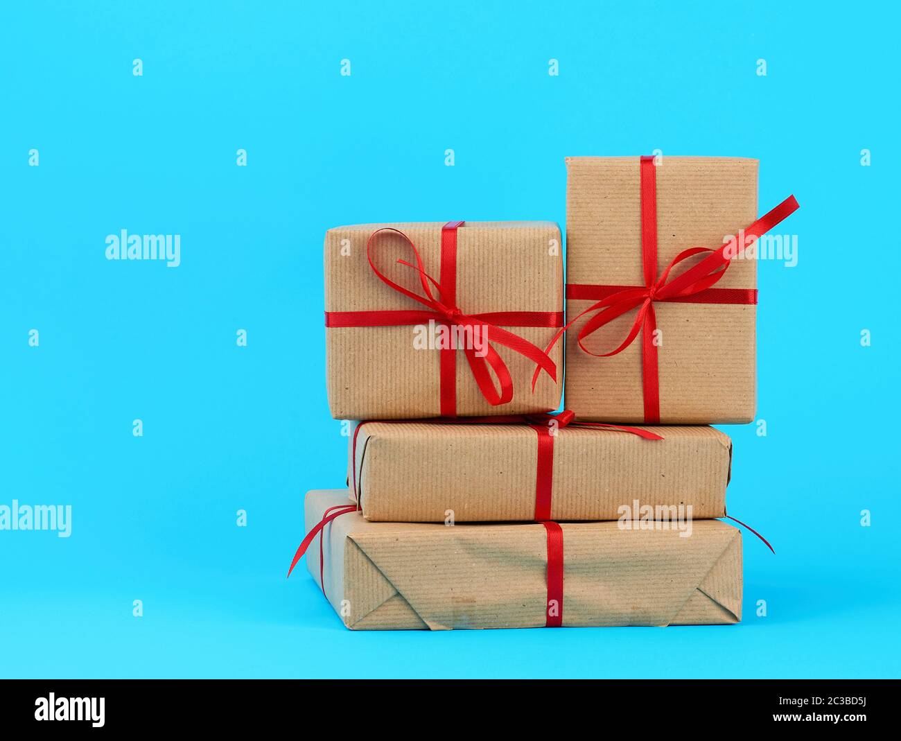 Stapel von Kisten in braunem Papier gewickelt und gebunden mit einem roten Bogen, Geschenke auf einem blauen Hintergrund. Tolles Design für irgendwelche Zwecke. Urlaub Hintergrund. Valentin Stockfoto
