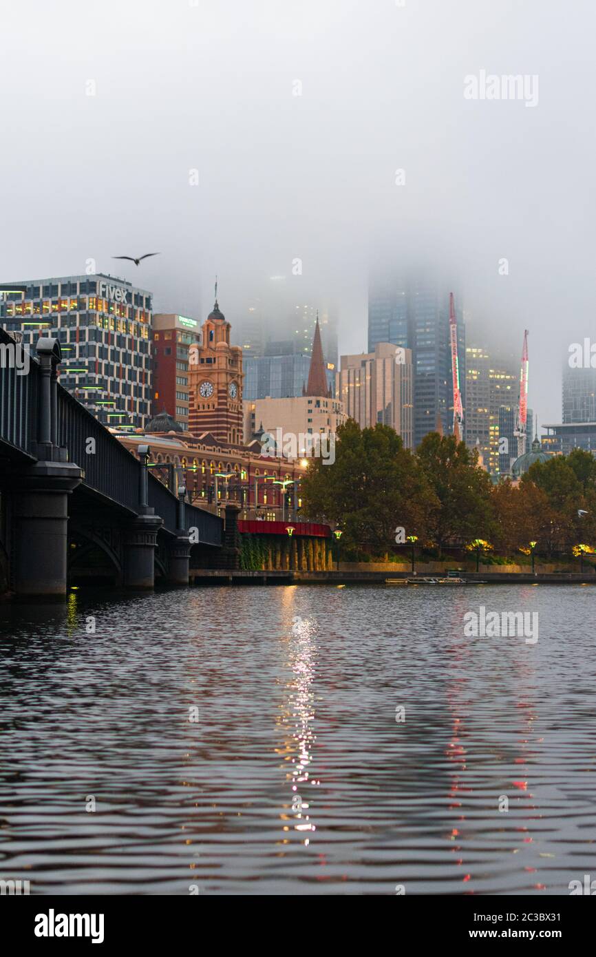 MELBOURNE, AUSTRALIEN - 14. April 2019: Flinders Street Station an einem kalten Morgen mit Nebel über dem zentralen Geschäftsviertel von Melbourne. Stockfoto