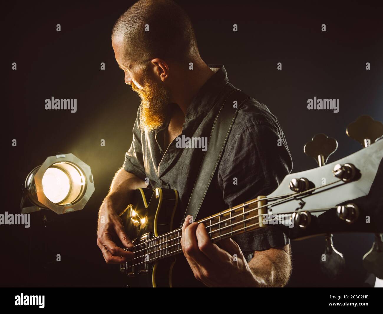 Foto eines bärtigen Mannes, der auf der Bühne vor Scheinwerfern E-Gitarre spielt. Stockfoto