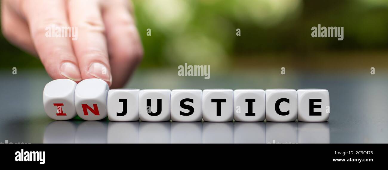 Hand dreht Würfel und ändert das Wort "Ungerechtigkeit" in "Gerechtigkeit". Stockfoto