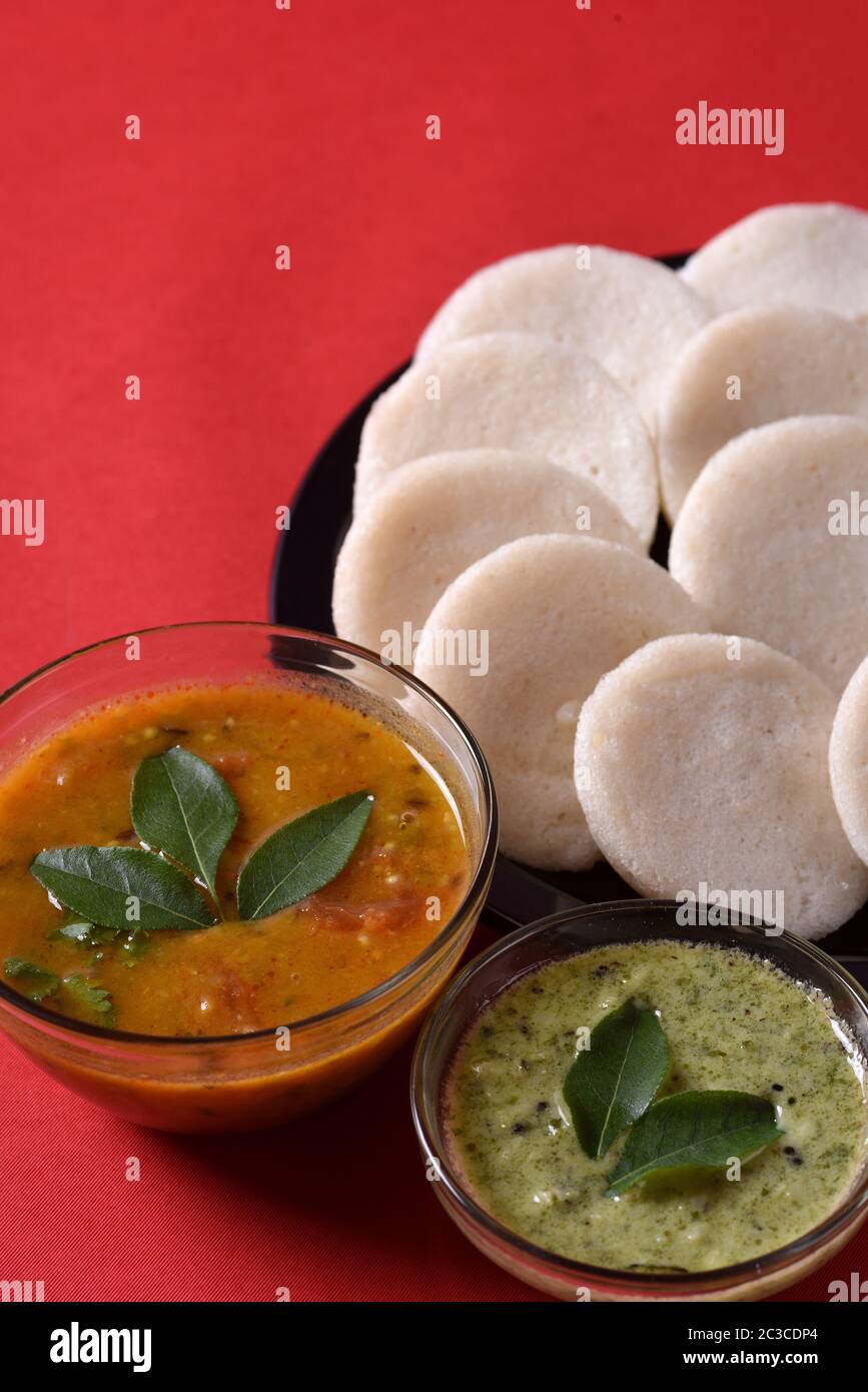 Idli mit Sambar und Kokos Chutney auf rotem Hintergrund, indische ...