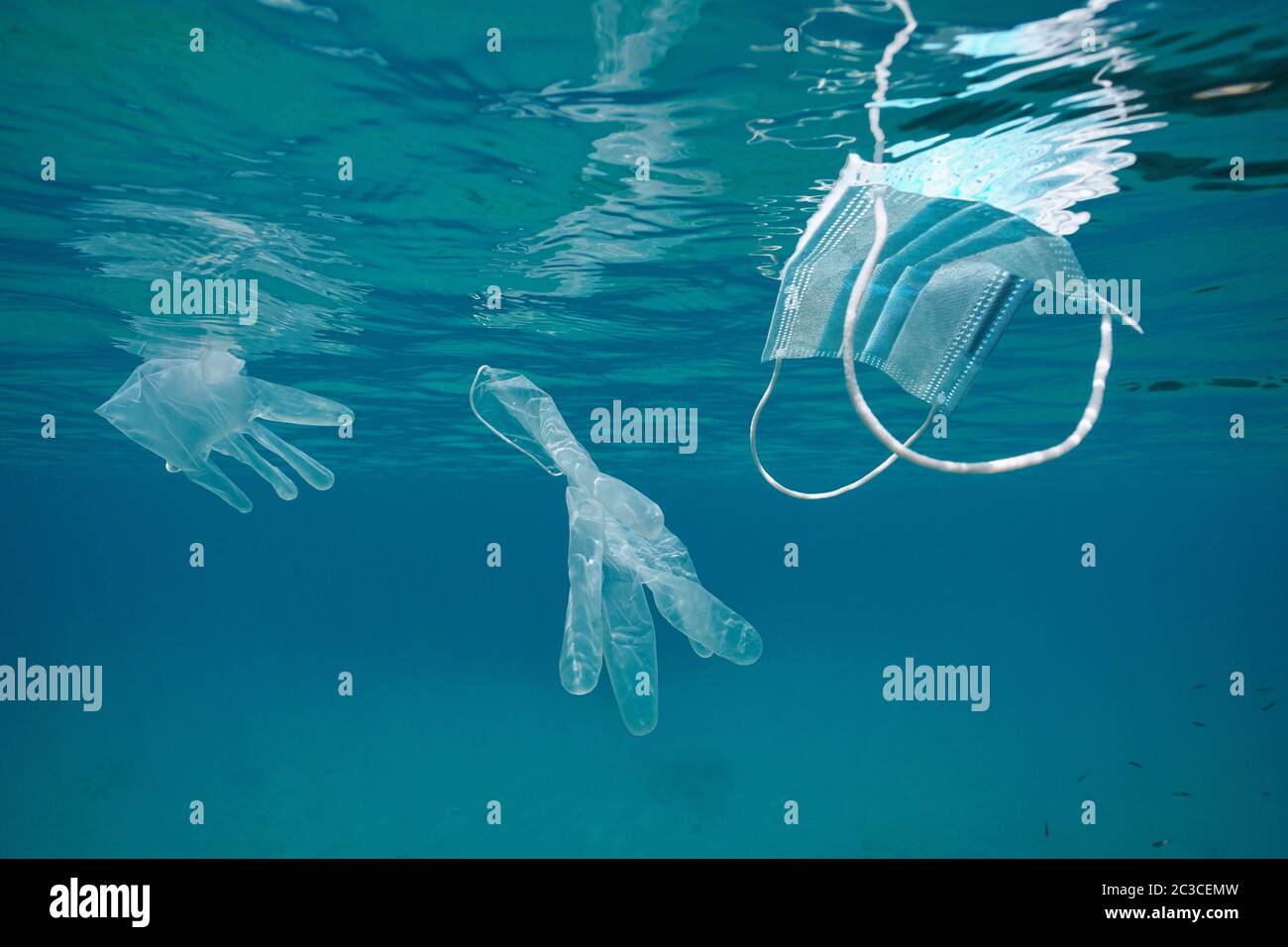 Gesichtsmaske und Handschuhe unter Wasser im Meer, Plastikmüll Verschmutzung im Wasser seit Coronavirus COVID-19 Pandemie Stockfoto