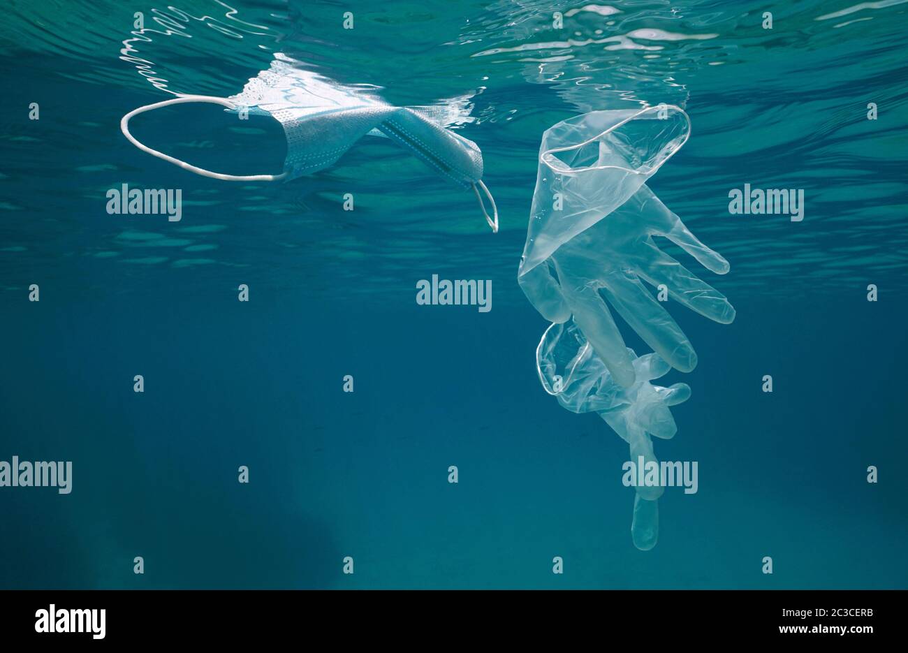 Handschuhe und Gesichtsmaske unter Wasser im Meer, Plastikmüll Verschmutzung seit Coronavirus COVID-19 Pandemie Stockfoto