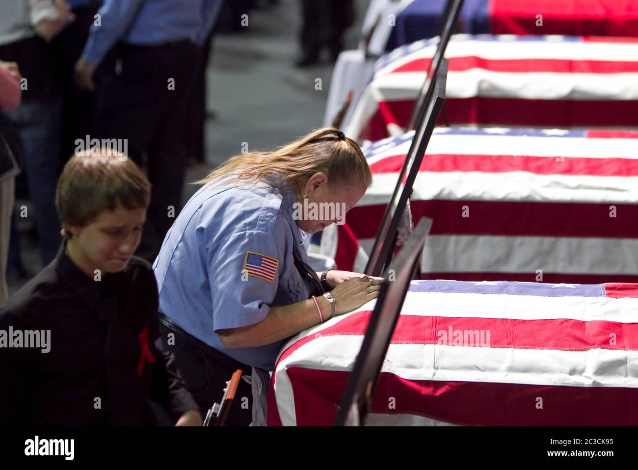 Waco Texas, USA, 25. April 2013: Während die Menge zu einer gemeinschaftsweiten Gedenkfeier kommt, sehen Trauernde Fotos und Särge von Feuerwehrleuten, die bei der Explosion der Düngemittelfabrik am 17. April in West, Texas getötet wurden. ©Marjorie Kamys Cotera/Daemmrich Photography Stockfoto