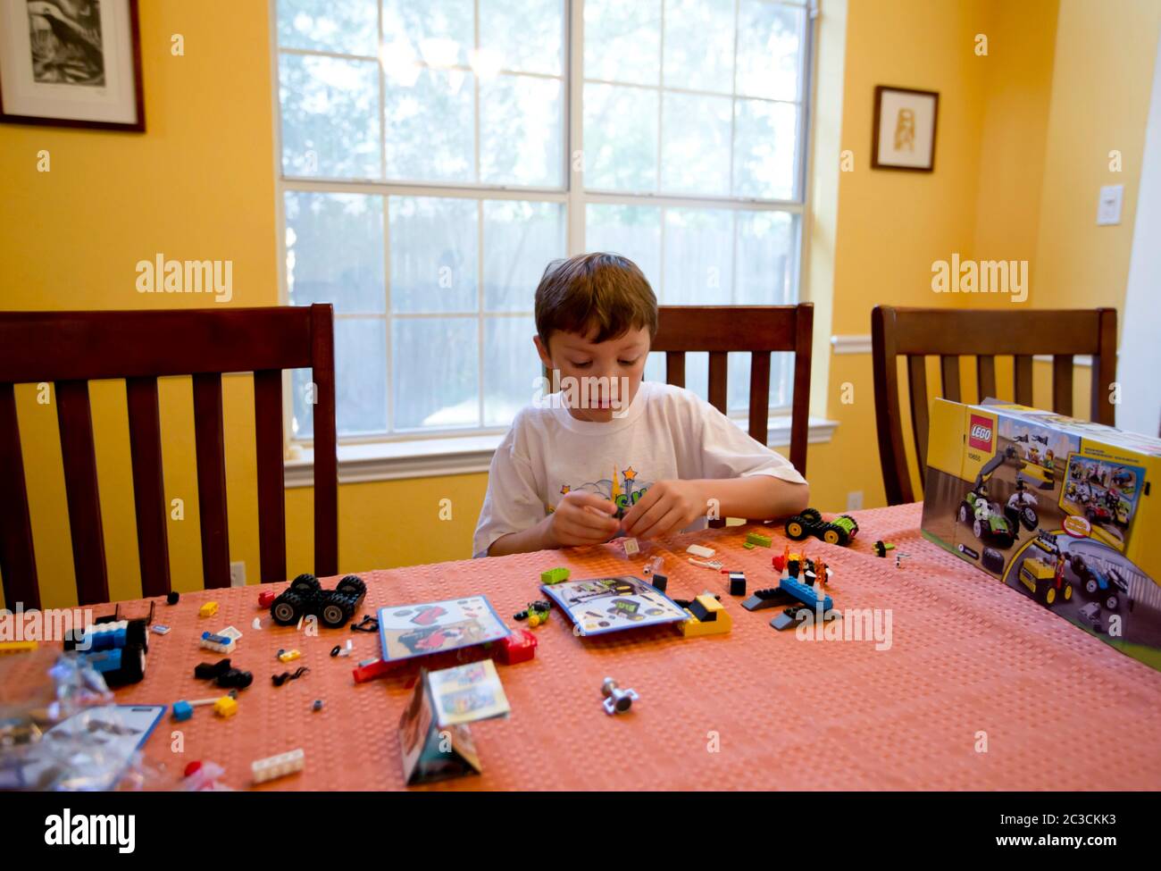 Der 7-jährige mexikanisch-amerikanische Junge spielt, baut und schaut sich Box an, um herauszufinden, wie man ein Lego-Set zu Hause zusammenstellt. Model veröffentlicht. mkc / Daemmrich Fotos Stockfoto