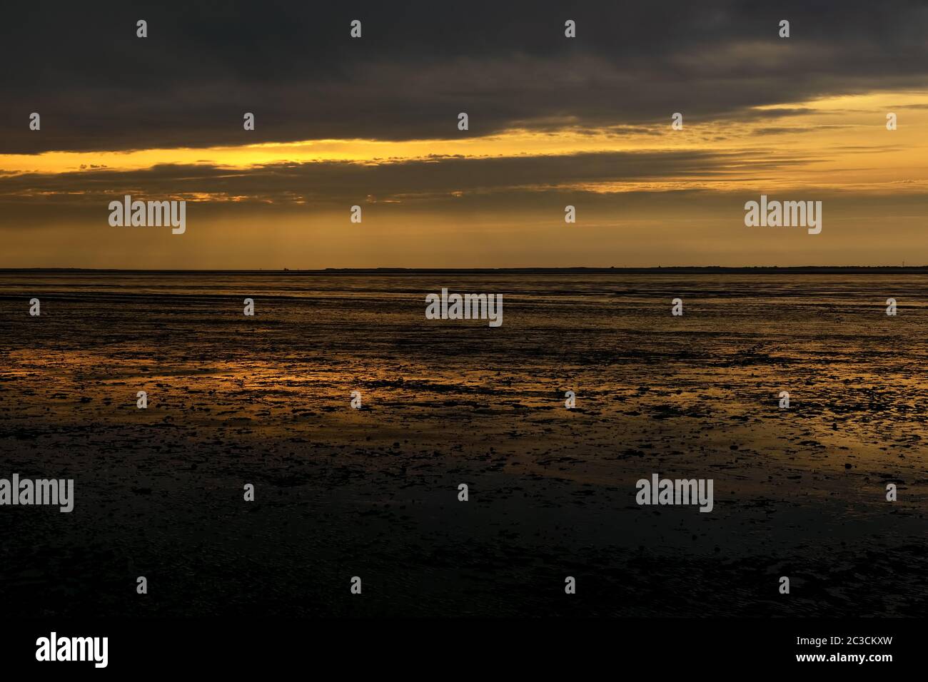 Reflexionen des Sonnenuntergangs am Ebbe-Strand Stockfoto